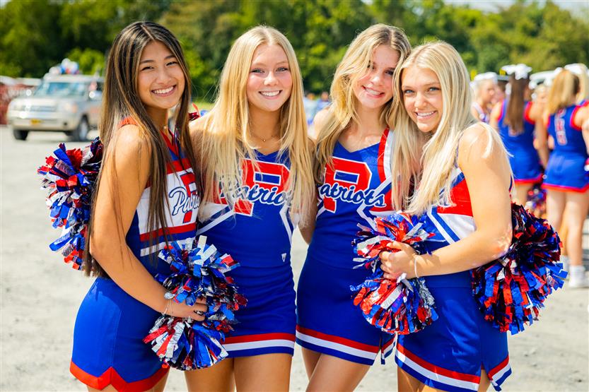 Four girls in cheerleading uniforms smile